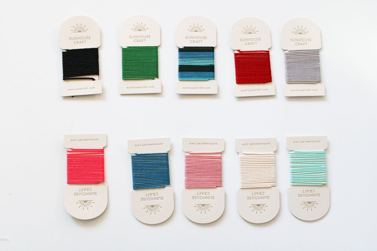 rows-of-threads-with-black-green-two-tone-red-grey-pink-scarlet-teal-white-dust-blue